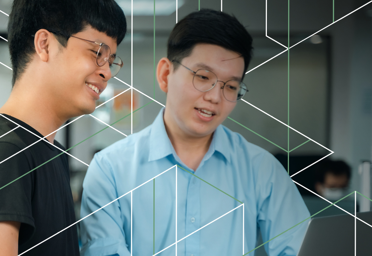 Two developers looking at a laptop with geometric lines framing their faces